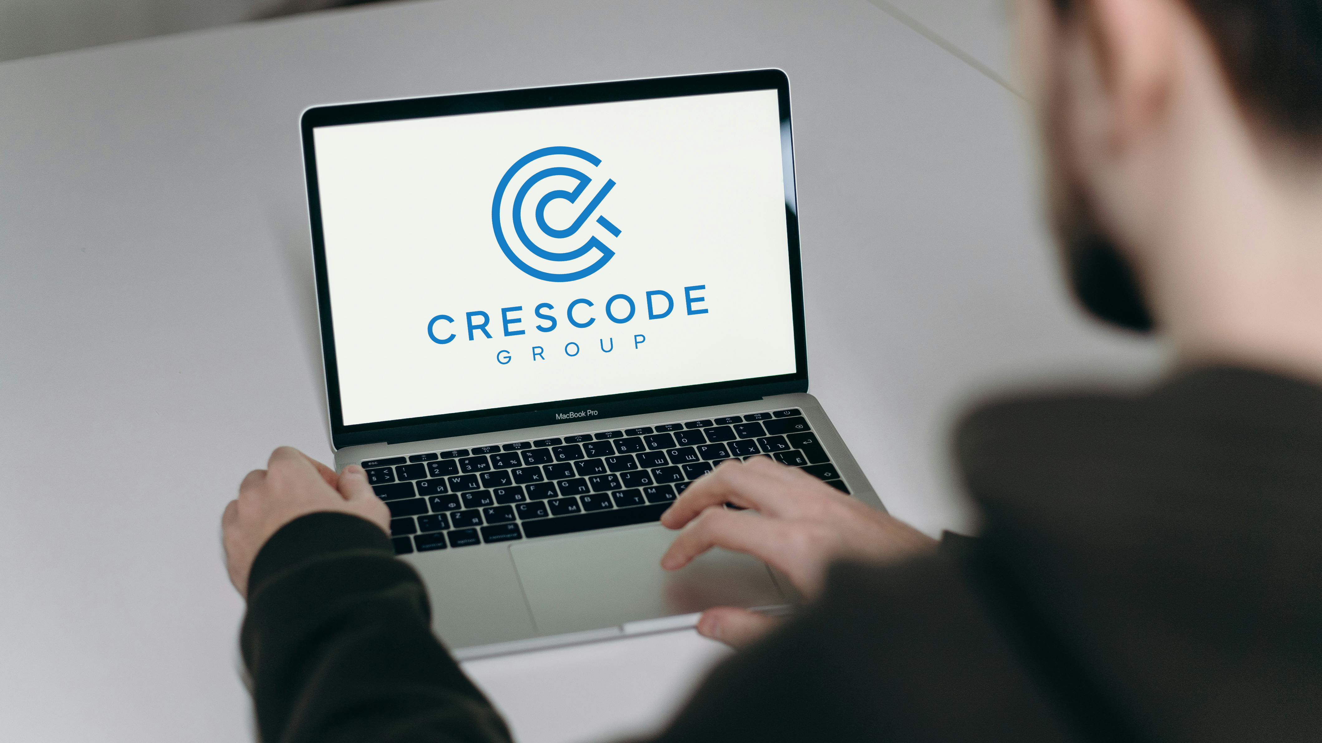Developer working on a MacBook with the Crescode Group logo